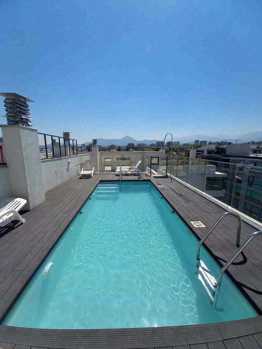 Piscina de largo en azotea con deck de madera y vista a la cordillera
